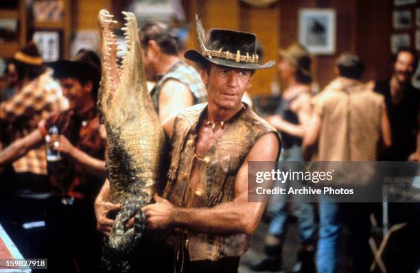 Paul Hogan carrying dead crocodile in bar in a scene from the film 'Crocodile Dundee', 1986.