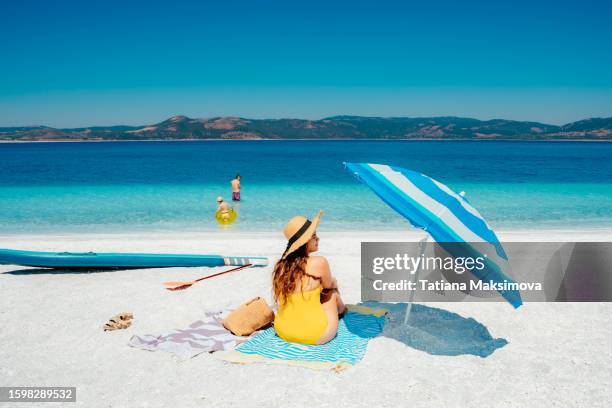 the family is relaxing on the white beach. yellow and blue colors. - family at beach stock pictures, royalty-free photos & images