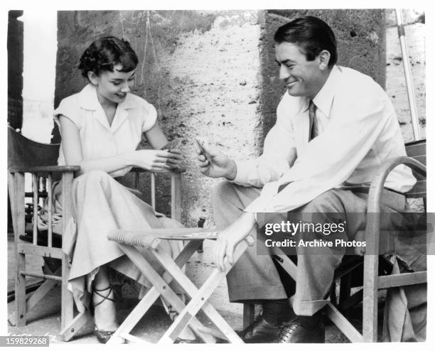 Audrey Hepburn plays cards with Gregory Peck in a scene from the film 'Roman Holiday', 1953.