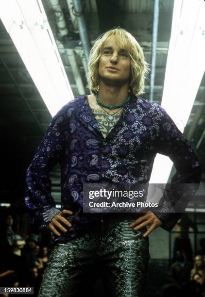 Owen Wilson with his hands on his hips wearing a paisley shirt and snakes skin pants in a scene from the film 'Zoolander', 2001.