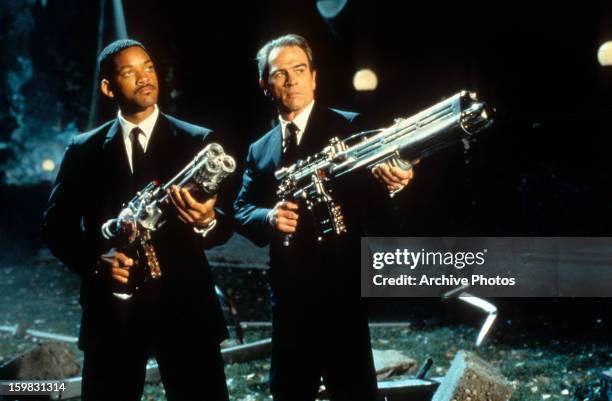 Will Smith and Tommy Lee Jones aiming their weapons towards the sky in a scene from the film 'Men In Black', 1997.