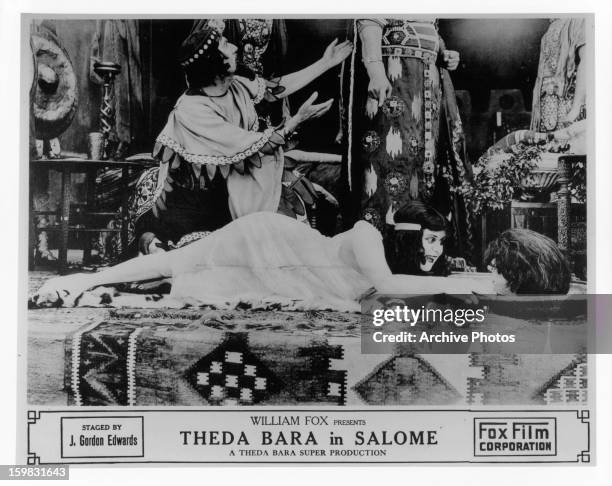 Theda Bara laughs at a severed head in a scene from the film 'Salome', 1918.