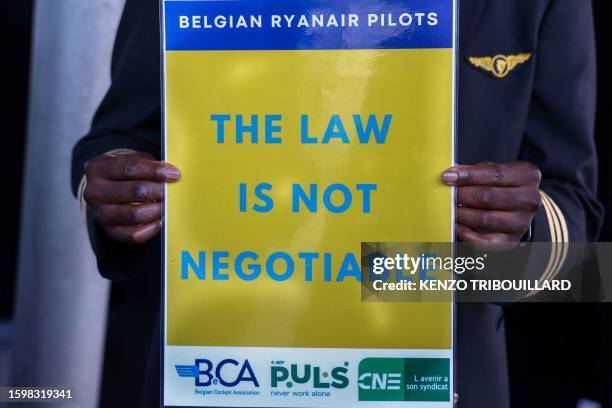 Ryanair pilot holds a placard at the Charleroi Airport, in Charleroi on August 14, 2023 during a Ryanair pilots' strike over working conditions.