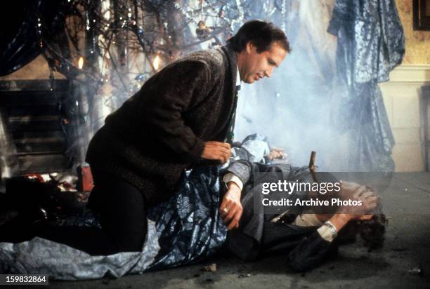 Chevy Chase sits over a man in a scene from the film 'Christmas Vacation', 1989.