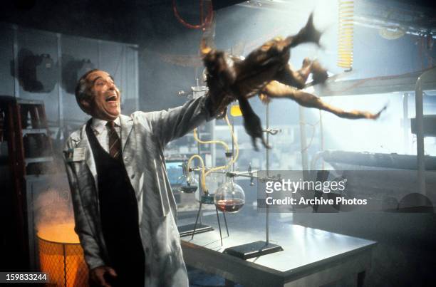 Christopher Lee attempts to thrown a gremlin off of his arm in a scene from the film 'Gremlins 2: The New Batch', 1990.