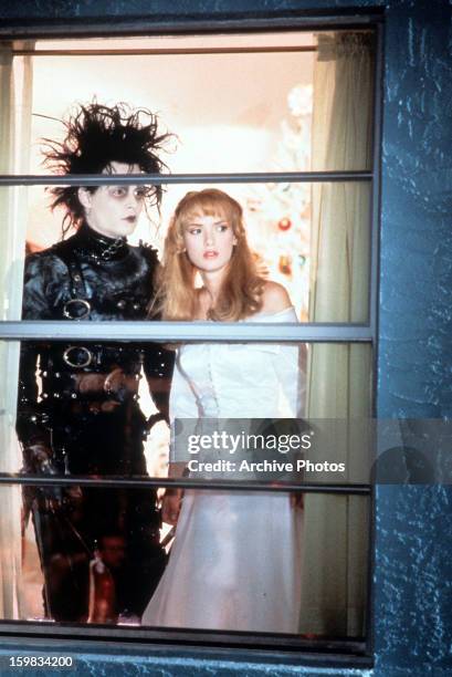 Johnny Depp and Winona Ryder looking out window in a scene from the film 'Edward Scissorhands', 1990.