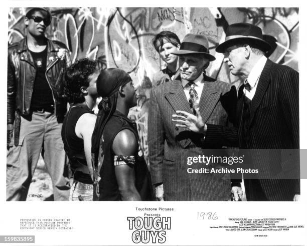 Kirk Douglas and Burt Lancaster talk to thugs in a scene from the film 'Tough Guys', 1986.