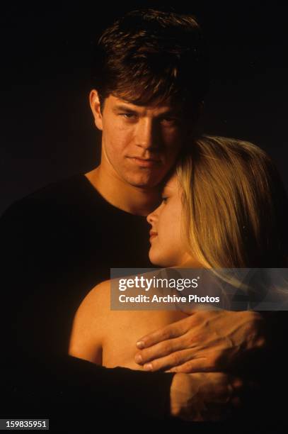 Mark Wahlberg holding Reese Witherspoon in publicity portrait for the film 'Fear', 1996.