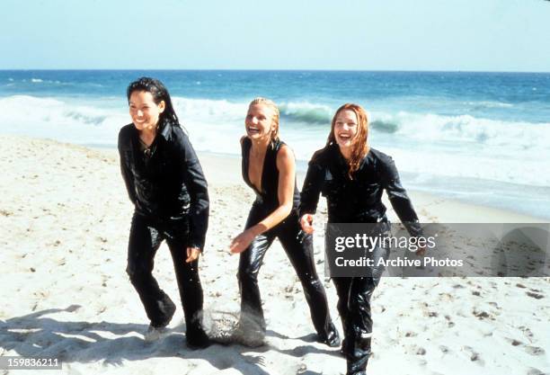Cameron Diaz, Drew Barrymore and Lucy Liu walking up the sand of a beach in a scene from the film 'Charlie's Angels', 2000.