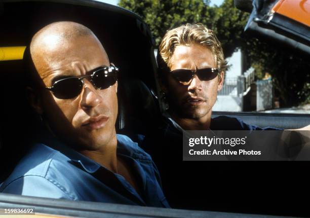 Vin Diesel and Paul Walker looking from car in a scene from the film 'The Fast And The Furious', 2001.