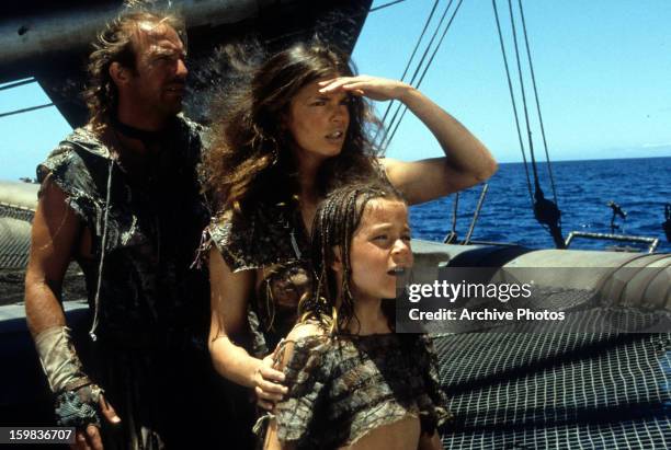 Kevin Costner, Jeanne Tripplehorn and Tina Majorino look to the horizon in a scene from the film 'Waterworld', 1995.