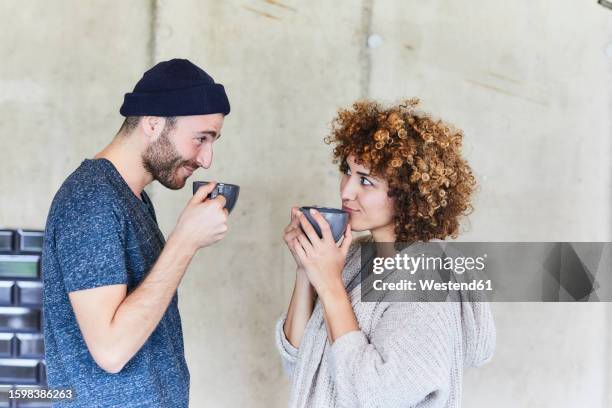 man and woman drinking coffee and smiling at each other - flirten stock-fotos und bilder