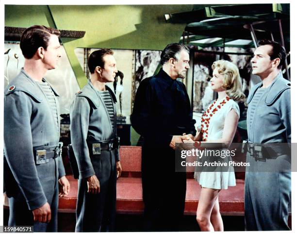 Leslie Nielsen watches as Walter Pidgeon greets Anne Francis in a scene from the film 'Forbidden Planet', 1956.