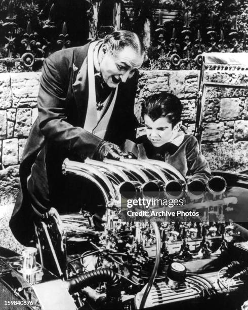 Al Lewis and Butch Patrick working on an engine together in a scene from the television series 'The Munsters', circa 1964.