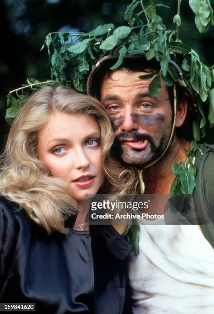Cindy Morgan and Bill Murray nestled behind a tree in a scene from the film 'Caddyshack', 1980.