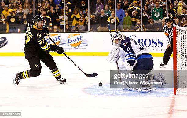 Patrice Bergeron of the Boston Bruins shoots the second shootout goal on Ondrej Pavelec of the Winnipeg Jets before scoring during the game on...