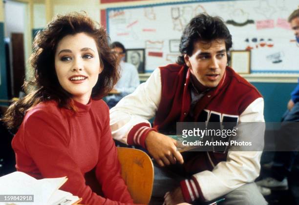 Shannen Doherty sits in front of a boy in class in a scene from the film 'Heathers', 1988.