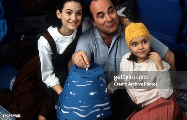 Winona Ryder, Bob Hoskins, and Christina Ricci gathered around lamp in a scene from the film 'Mermaids', 1990.