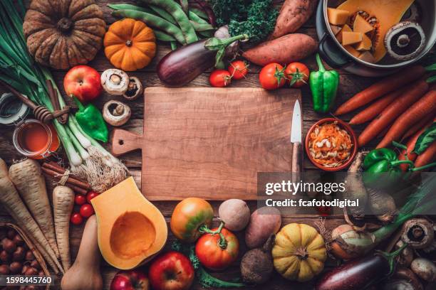 empty cutting board at the center of fresh organic autumnal vegetables background. copy space - pratos vegetarianos imagens e fotografias de stock