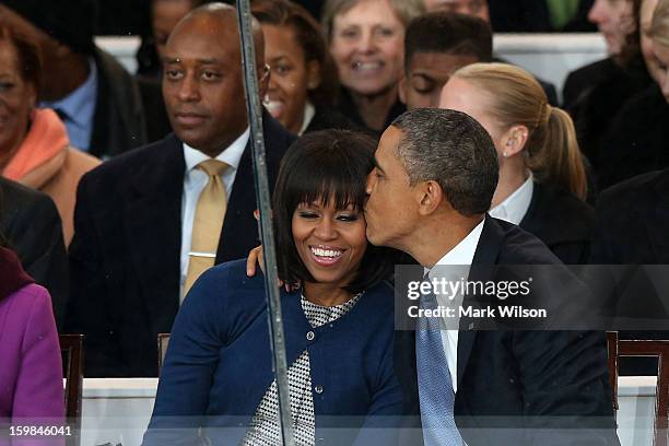 President Barack Obama kisses first lady Michelle Obama on the reviewing stand as the presidential inaugural parade winds through the nation's...