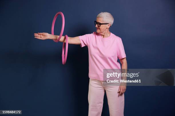 senior woman practicing with hoops against blue background - sportlichkeit stock-fotos und bilder