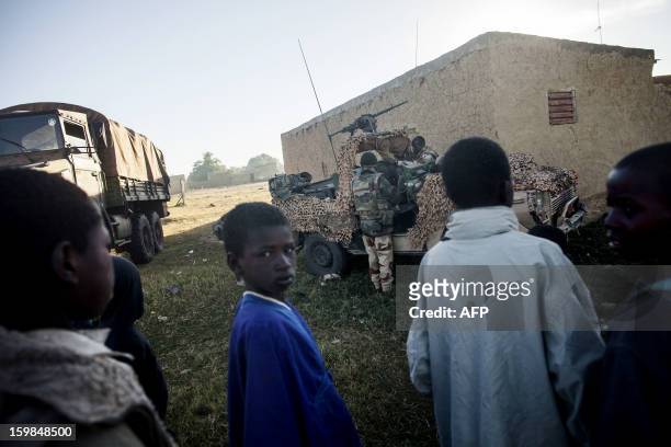 Malian children look on as French Legionaire check their gear at an improvised helipad as groups from various units of the Air Force, Ground Army and...