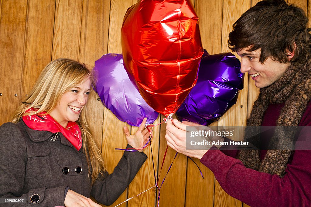 A young couple with colorful heart balloons.