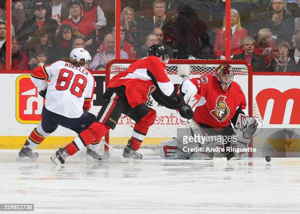 Craig Anderson of the Ottawa Senators makes a save as teammate Chris Phillips and Peter Mueller of the Florida Panthers battle for the rebound on...