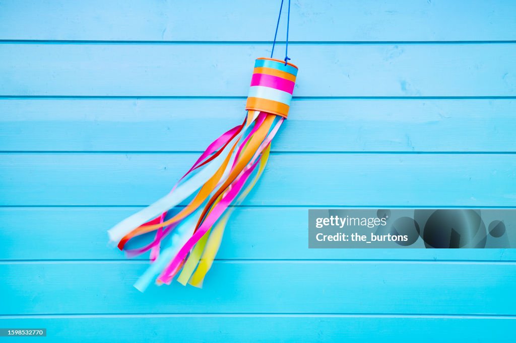Colorful self-made wind chime hanging at a blue wooden wall