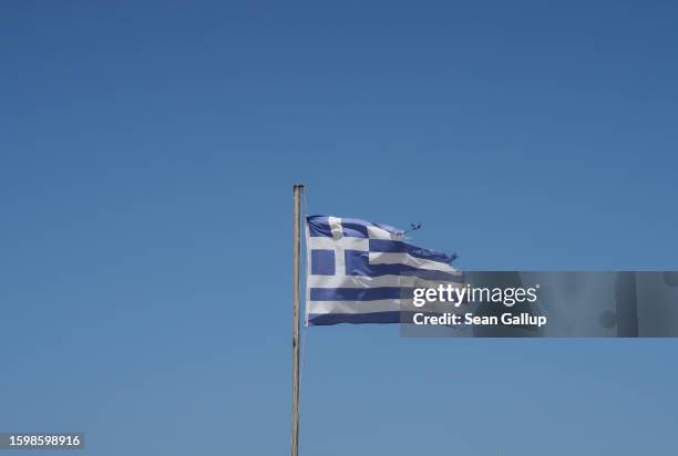 Tattered Greek flag flies over a beach on July 31, 2023 near Sidari, Greece. Corfu island is a popular tourist destination.