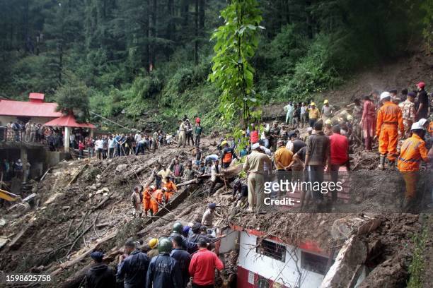 National Disaster Response Force personnel search for victims at the site of a landslide after a temple collapsed due to heavy rains in Shimla on...