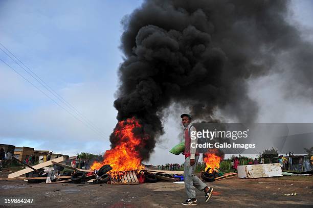Protestor passing a heap of burning tires on January 21 in Sasolburg, South Africa. Protesting broke out as a result of the announcement of the...