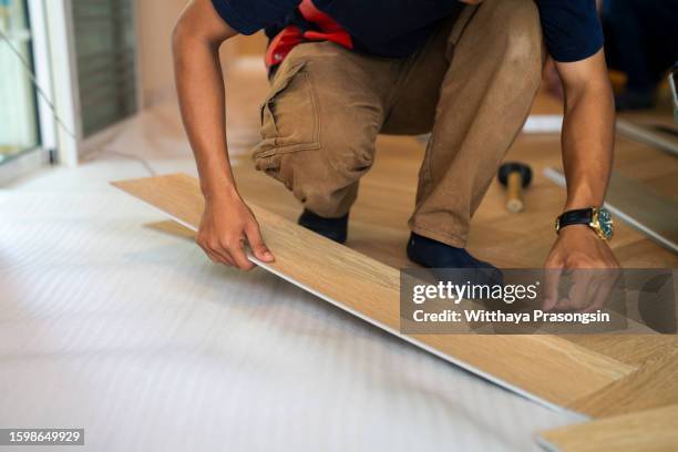 worker carpenter doing laminate floor work - pavimento-in-laminato foto e immagini stock