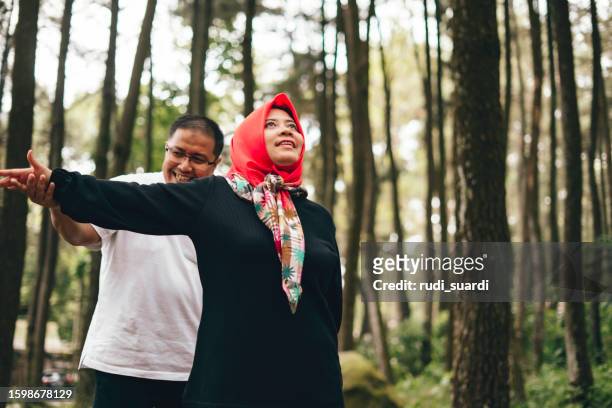 asiatisches reifes paar, das sich zusammen im wald ausdehnt - red scarf stock-fotos und bilder