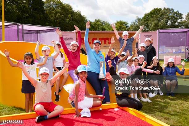 Champion Ashleigh Buhai of South Africa poses with local school children in the Festival Village prior to the AIG Women's Open at Walton Heath Golf...