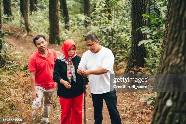 caminata de adultos maduros asiáticos a través del bosque - pañuelo rojo fotografías e imágenes de stock