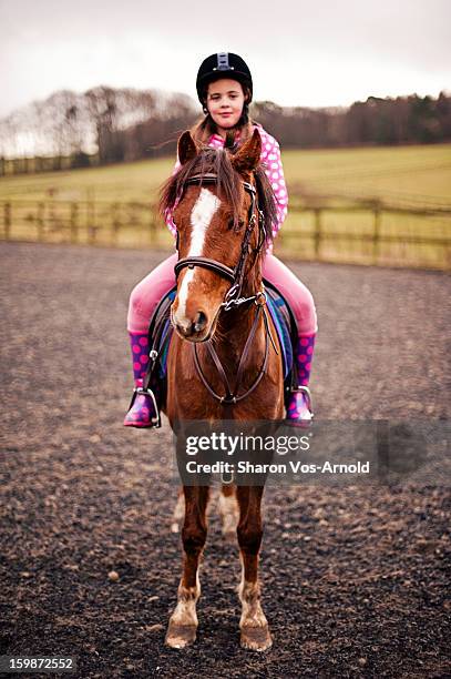 girl riding pretty chestnut pony in sandschool - motorized vehicle riding stock pictures, royalty-free photos & images