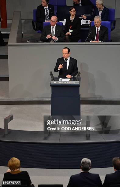 French President Francois Hollande delivers a speech in front of German Chancellor Angela Merkel during a joint session of the French National...