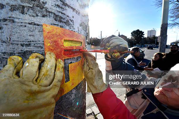 Volunteers from the 'Fédération Française de Randonnée Pédestre' mark the path of the GR2013 hiking route with red and yellow paint, in Marseille, on...