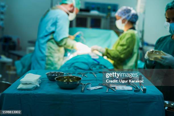 sterile table holding surgical equipment in the operating room - surgical tray stock pictures, royalty-free photos & images