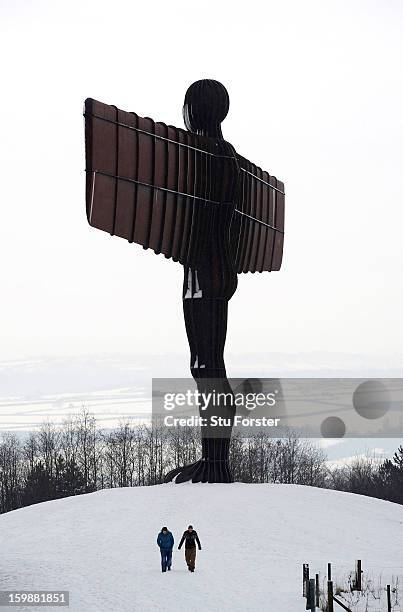 People walk through the snow past Antony Gormley's sculpture 'The Angel of the North' on January 22, 2013 in Gateshead, England.