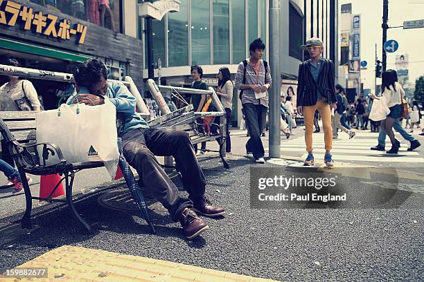 Man takes a nap on a street side bench in Tokyo's Harajuku Fashion District