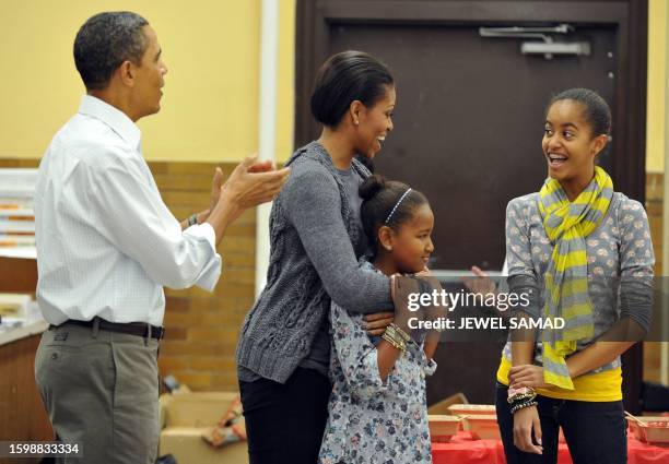 President Barack Obama, along with others, sings "Happy Birthday" to First Lady Michelle Obama as their daughters Malia and Sasha look on as they...