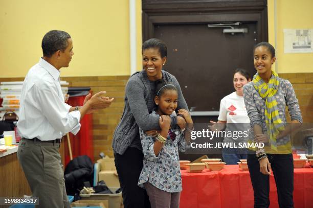 President Barack Obama, along with others, sings "Happy Birthday" to First Lady Michelle Obama as their daughters Malia and Sasha look on as they...