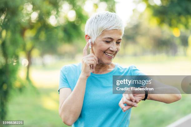 ältere frau im park joggen - pedometer stock-fotos und bilder