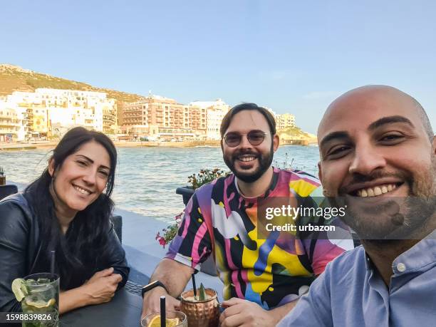 group of friends taking a selfie in a seaside café - gozo malta stock pictures, royalty-free photos & images