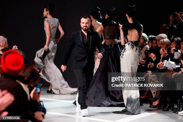 French designer Julien Fournie walks past models as he acknowledges the public at the end of his Haute Couture Spring-Summer 2013 collection shows on...