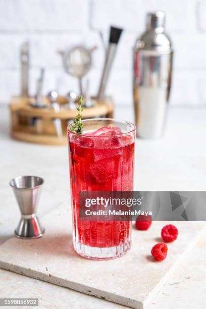 red raspberry gin cocktail longdrink lemonade soda drink with berries and thyme on bright kitchen counter - raspberry cocktail stock pictures, royalty-free photos & images