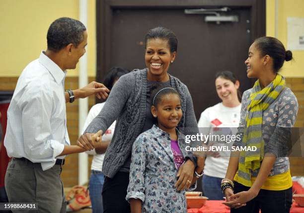 President Barack Obama along with others sings "Happy Birthday" to First Lady Michelle Obama as their daughters Malia and Sasha look on as they...