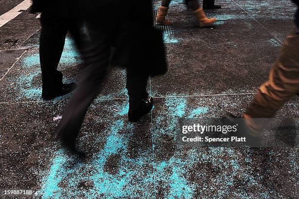 Pedestrians walk over blue salt on the sidewalk after a light snow fall on one of the coldest days of the year on January 22, 2013 in New York City....